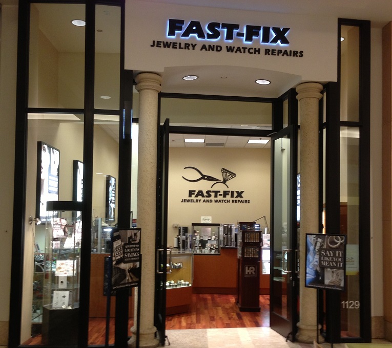 Picture of Fast-Fix storefront at South Center Mall. Two pillars with Fast-Fix Jewelry and watch Repairs logo on top. Windows on the sides that let the customer see through the store.