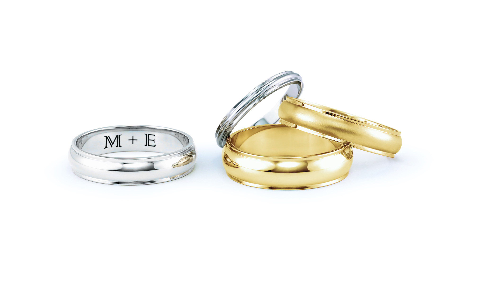 Four wedding bands, 2 gold and 2 platinum. One shows an engraved sentence: M+E