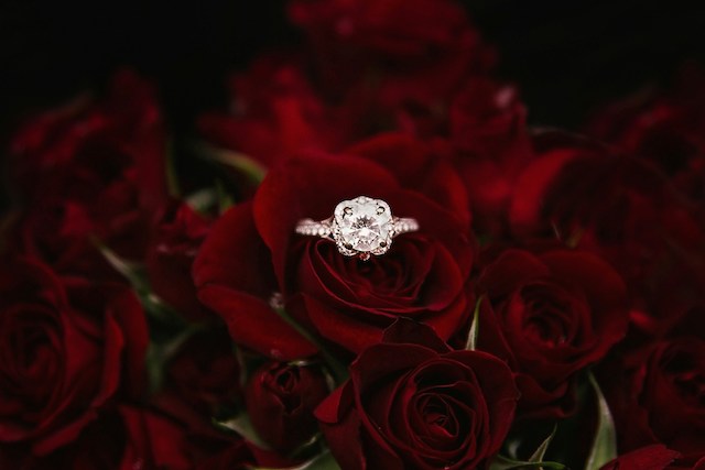 An engagement ring inside of a bouquet of red roses.