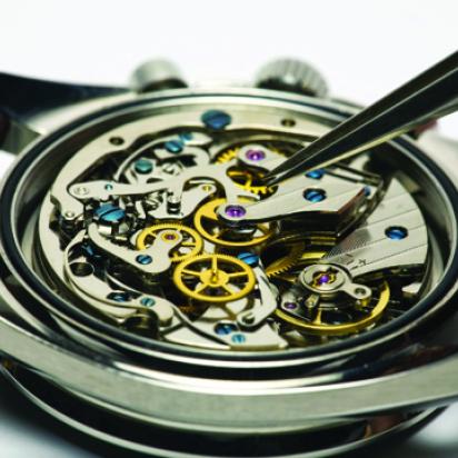 Inside of an automatic watch being repaired with tweezers.